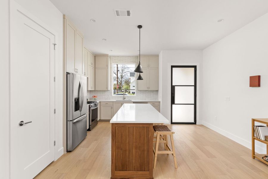 Two tone kitchen featuring a center island, stainless steel appliances, light wood-style floors, pendant lighting, and two tone color scheme Two tone kitchen featuring a center island, stainless steel appliances, light wood-style floors, pendant lighting, and two tone color scheme