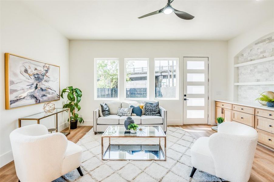 Living room featuring ceiling fan, built in shelves, and light hardwood / wood-style flooring