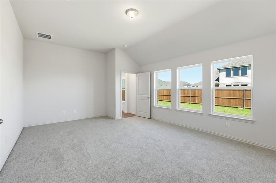 Empty room featuring light colored carpet and vaulted ceiling