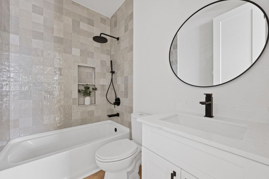 Full bathroom featuring a tiled shower surround, recessed shower niche, and matte black fixtures