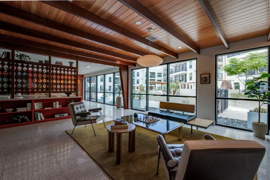 This living area features a distinctive wood-beamed ceiling and large windows that provide an abundance of natural light