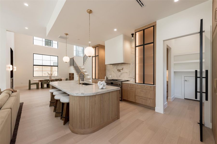 The oversized island anchors the kitchen with generous prep and gathering space, while the full butler’s pantry sits discreetly beyond, keeping additional prep, storage and cleanup out of the main view. The oversized island anchors the kitchen with generous prep and gathering space, while the full butler’s pantry sits discreetly beyond, keeping additional prep, storage and cleanup out of the main view.