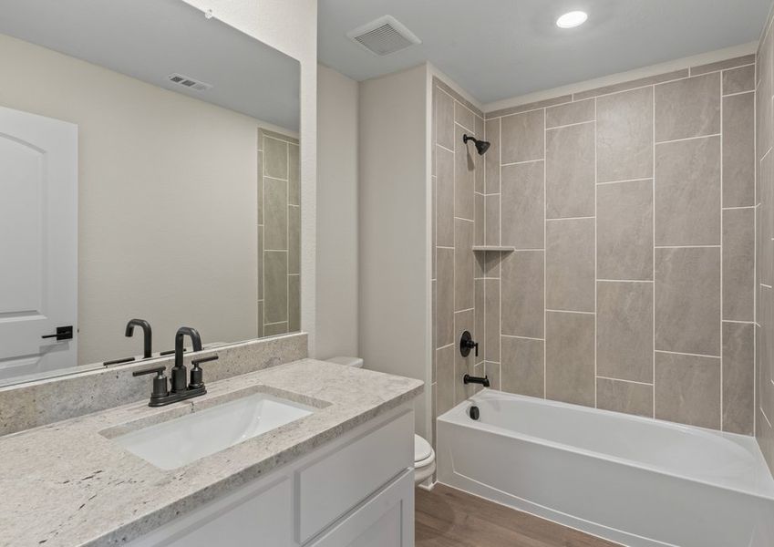 The secondary bathroom has a large vanity space and a shower-tub combo.