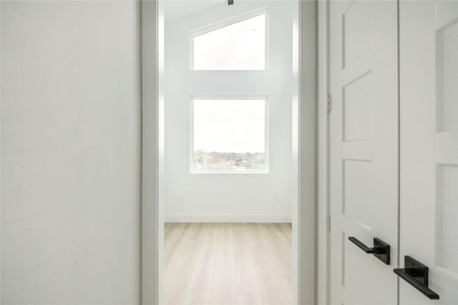 Corridor with plenty of natural light and light wood-style floors