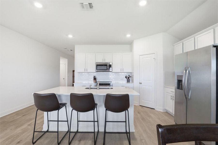 Central kitchen island with white countertop, stainless steel sink, and gooseneck faucet
