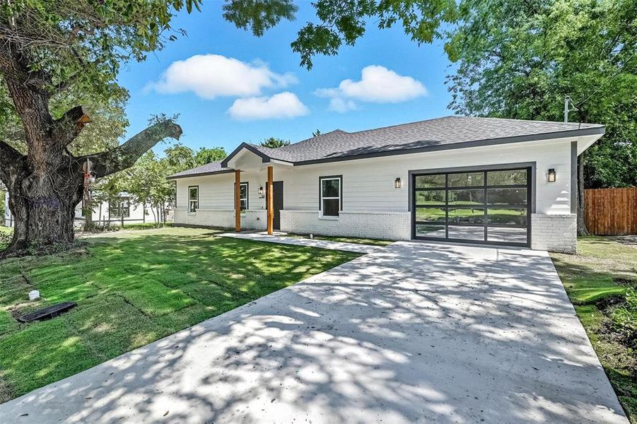 Modern farmhouse with brick siding, a shingled roof, and concrete driveway Modern farmhouse with brick siding, a shingled roof, and concrete driveway