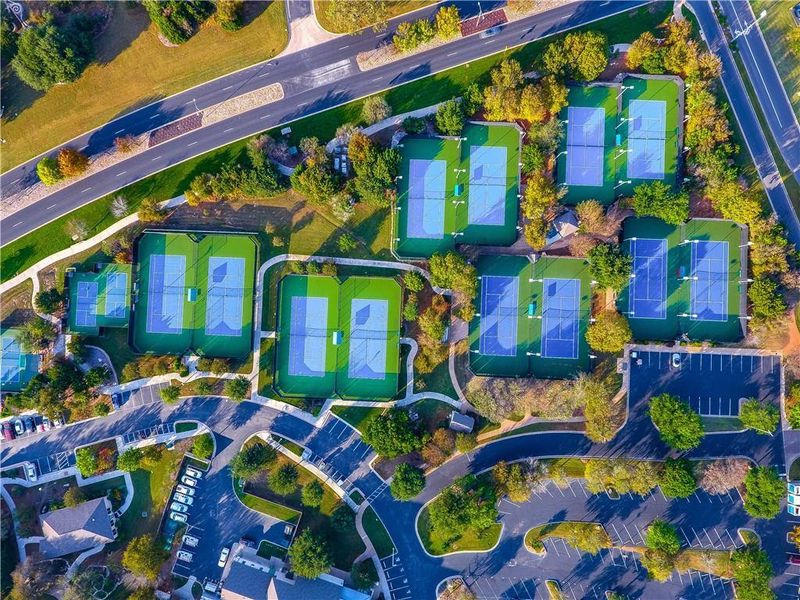 An aerial view showcases multiple tennis courts nestled within a vibrant, green landscape. An aerial view showcases multiple tennis courts nestled within a vibrant, green landscape.