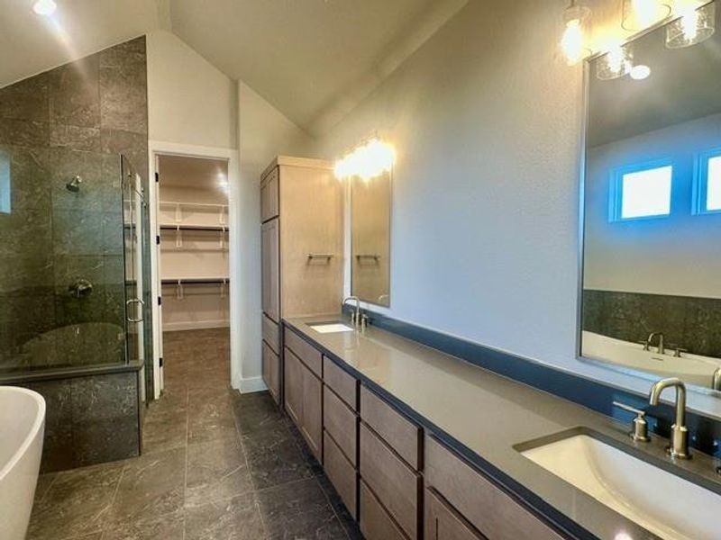 A primary bathroom featuring a spacious walk-in closet, a shower with floor-to-ceiling tile, and a dual-sink vanity with ample counter space. A primary bathroom featuring a spacious walk-in closet, a shower with floor-to-ceiling tile, and a dual-sink vanity with ample counter space.