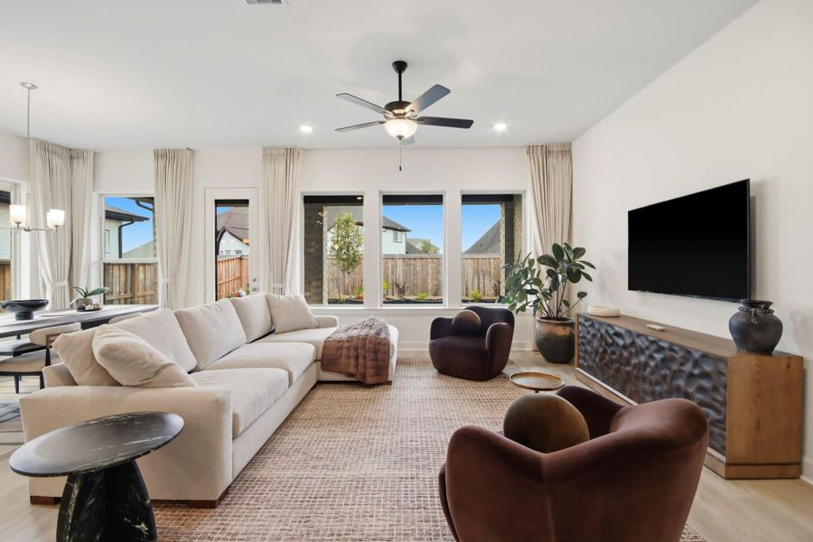 Welcoming living area with abundant natural light, featuring a modern ceiling fan, plush seating, and a large flat-screen TV, seamlessly connected to the dining space for effortless entertaining.