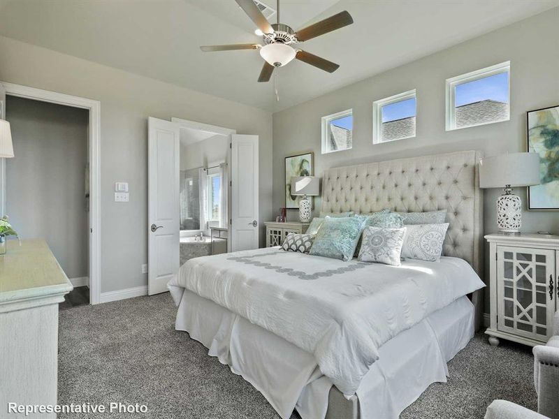 Carpeted bedroom featuring ensuite bathroom and ceiling fan