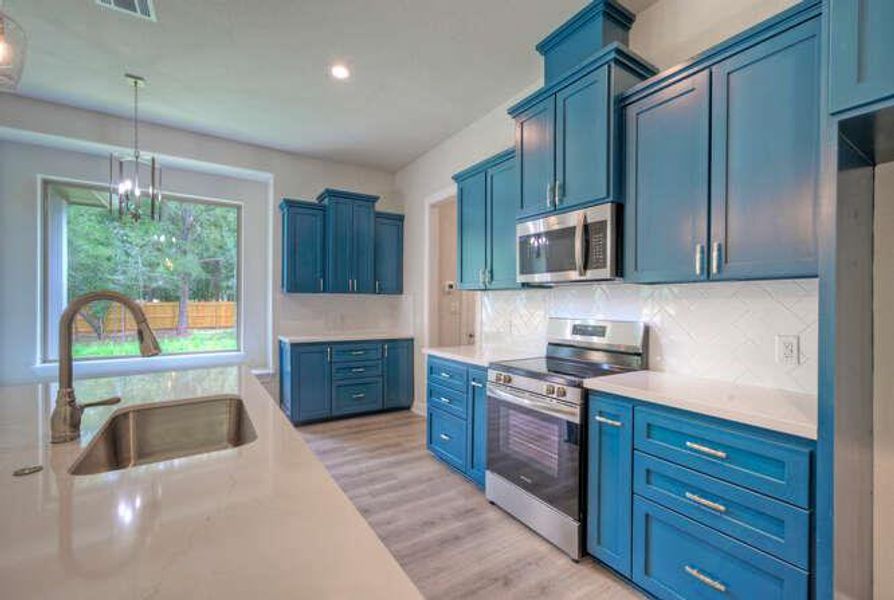Kitchen with stainless steel appliances, blue cabinetry, light countertops, tasteful backsplash, and recessed lighting