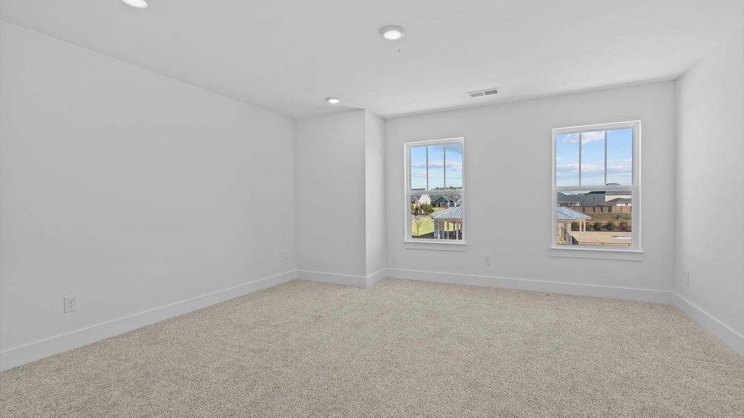 Notable bedroom offering soft carpet, a walk-in closet, and expansive windows overlooking the yard