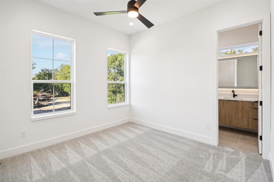 Unfurnished bedroom featuring ceiling fan, sink, and light colored carpet