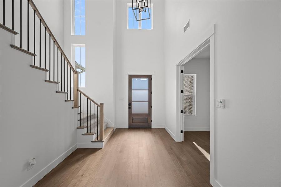 Entryway featuring wood-type flooring, a towering ceiling, and stairway