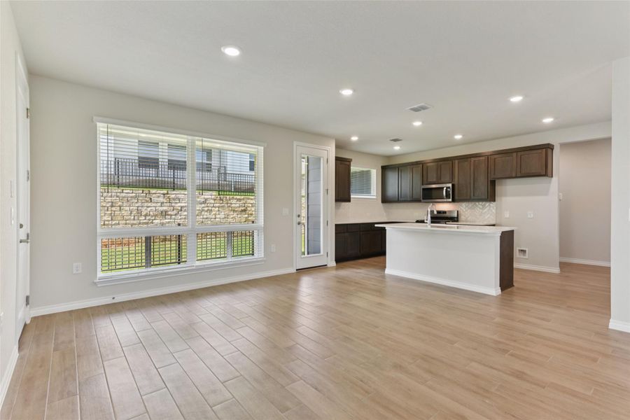Kitchen with an island with sink, dark brown cabinetry, recessed lighting, light wood-style flooring, and decorative backsplash Kitchen with an island with sink, dark brown cabinetry, recessed lighting, light wood-style flooring, and decorative backsplash