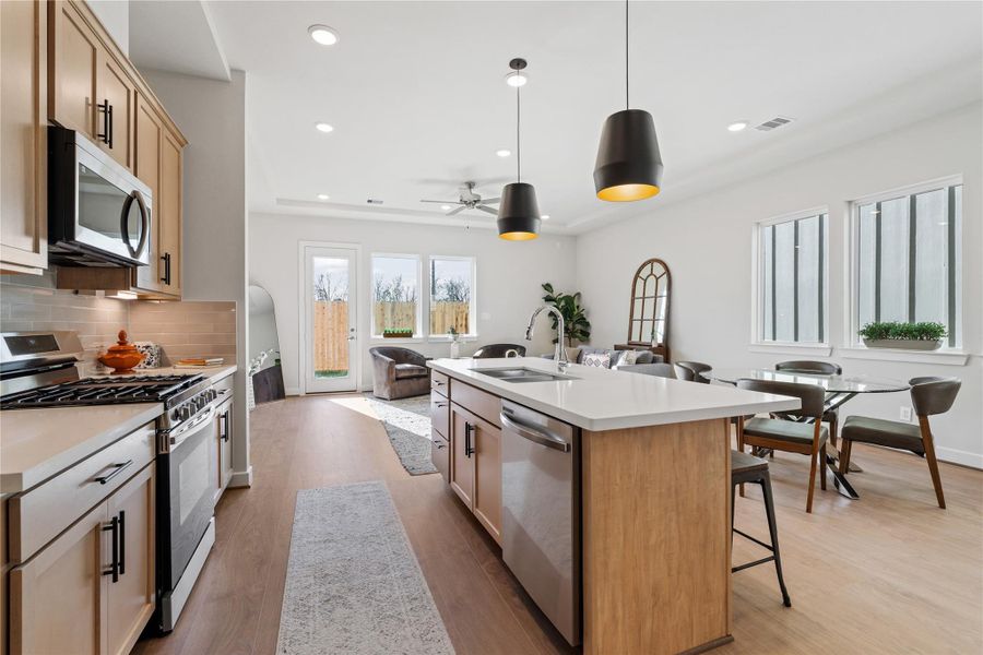 Looking from the range across the island toward the dining and living areas, the whole first floor reads as one connected space. Looking from the range across the island toward the dining and living areas, the whole first floor reads as one connected space.