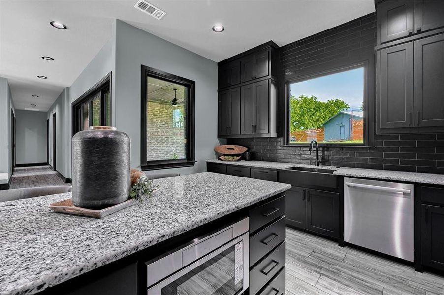 Kitchen featuring appliances with stainless steel finishes, a sink, light stone countertops, backsplash, and recessed lighting Kitchen featuring appliances with stainless steel finishes, a sink, light stone countertops, backsplash, and recessed lighting