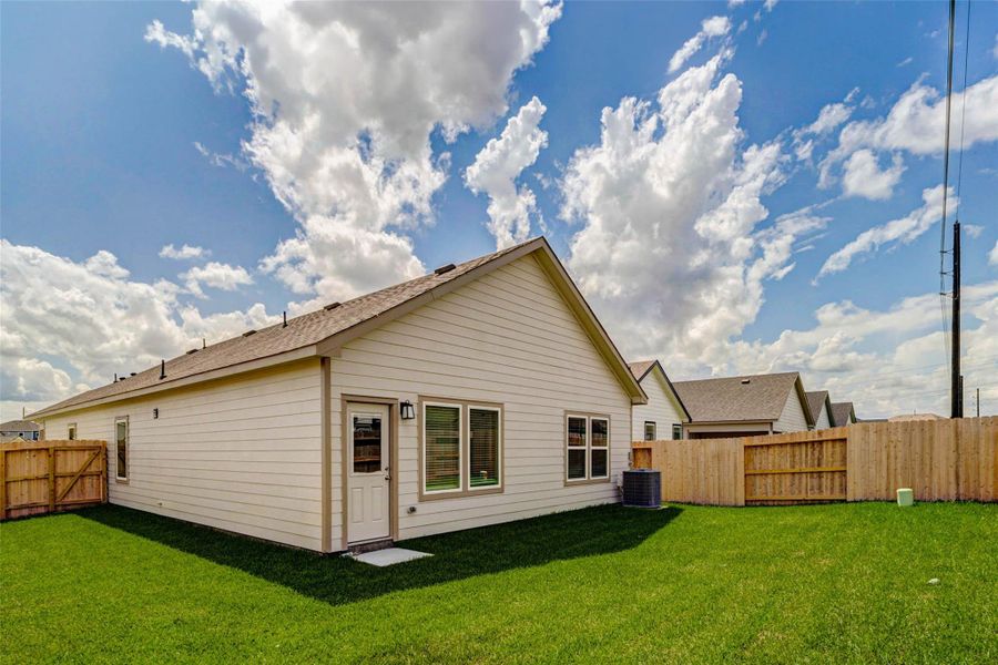 The backyard offers a spacious grassy area with a fully fenced perimeter, providing room to relax, play, garden, or entertain outdoors. The rear exterior includes multiple windows, a back door, and clean siding, while the wide lawn gives the home an inviting outdoor extension. The backyard offers a spacious grassy area with a fully fenced perimeter, providing room to relax, play, garden, or entertain outdoors. The rear exterior includes multiple windows, a back door, and clean siding, while the wide lawn gives the home an inviting outdoor extension.