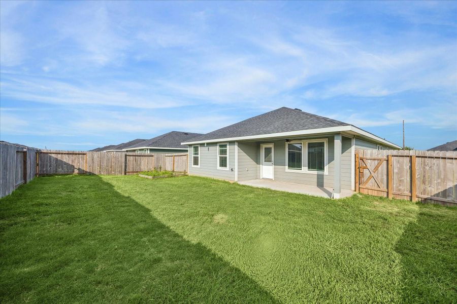 Spacious backyard with a well-maintained lawn and a wooden fence for privacy.