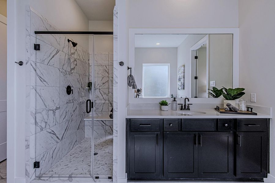 Glass-enclosed shower with tile surround and a spacious bathroom vanity