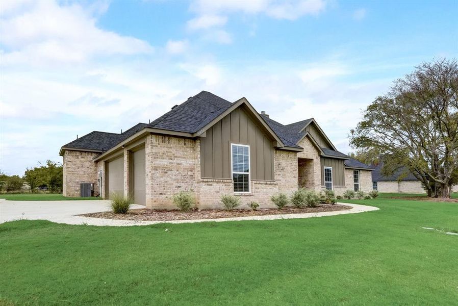 View of front facade with central AC, brick siding, board and batten siding, a front yard, and driveway View of front facade with central AC, brick siding, board and batten siding, a front yard, and driveway