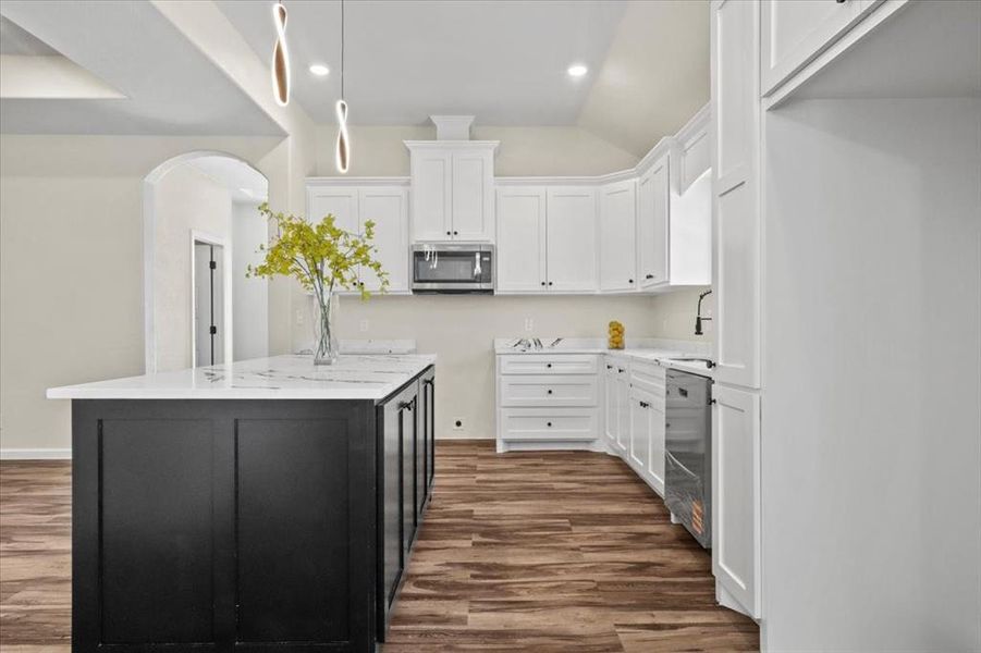 Kitchen with white cabinets, dark wood-type flooring, arched walkways, vaulted ceiling, and recessed lighting Kitchen with white cabinets, dark wood-type flooring, arched walkways, vaulted ceiling, and recessed lighting