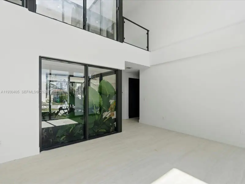 Double-height ceilings, floor-to-ceiling glass wall panels, large-format tile flooring, and a glass-paneled staircase railing Double-height ceilings, floor-to-ceiling glass wall panels, large-format tile flooring, and a glass-paneled staircase railing