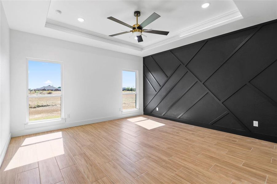 Unfurnished room featuring wood finish floors, a ceiling fan, a decorative wall, a raised ceiling, and recessed lighting Unfurnished room featuring wood finish floors, a ceiling fan, a decorative wall, a raised ceiling, and recessed lighting