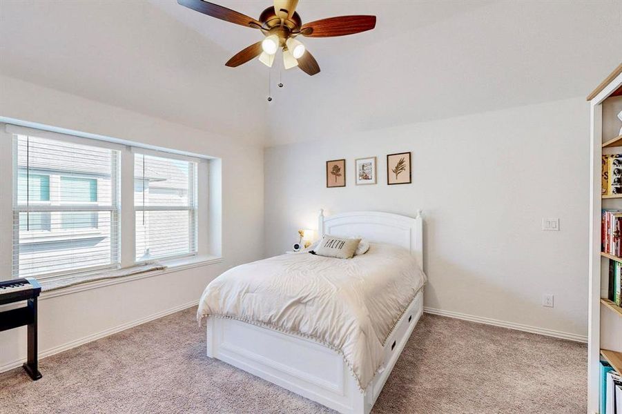 Bedroom with light carpet, a ceiling fan, and lofted ceiling