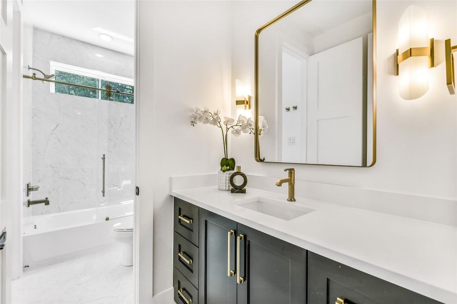 A statement in contemporary luxury, this spa-inspired bath showcases custom cabinetry with soft-close drawers, sleek quartz countertops, and brushed gold fixtures. The floor-to-ceiling marble tile shower/tub surround exudes sophistication, while the lighting design enhances the calm, restorative aesthetic—perfect for unwinding after along shift at the hospital or clinic.