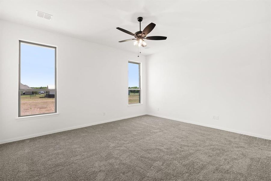 Carpeted spare room with a ceiling fan and baseboards Carpeted spare room with a ceiling fan and baseboards