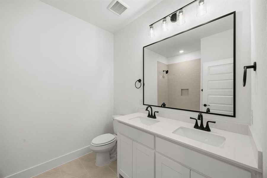 Bathroom featuring double vanity, light tile patterned floors, and a shower