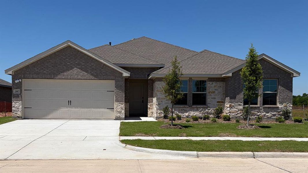 Single-story exterior featuring a gray brick and stone facade, a two-car garage, and a concrete driveway