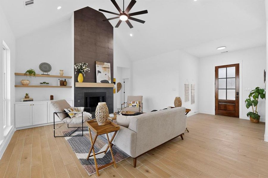 Living area featuring a large fireplace, high vaulted ceiling, light wood-type flooring, a ceiling fan, and recessed lighting