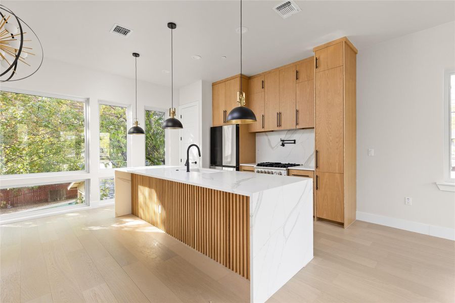 Natural wood cabinetry and a slatted island anchor this light-filled modern kitchen.