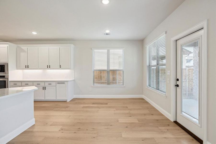 Kitchen with white cabinetry, light countertops, light wood-style flooring, stainless steel oven, and recessed lighting