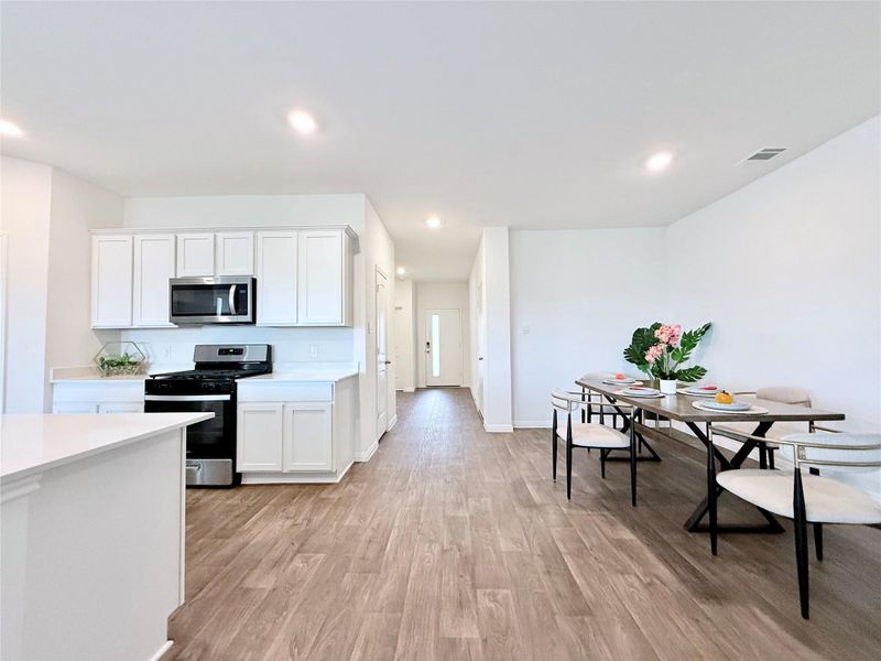 Kitchen featuring stainless steel appliances, white cabinetry, light wood-type flooring, and recessed lighting Kitchen featuring stainless steel appliances, white cabinetry, light wood-type flooring, and recessed lighting