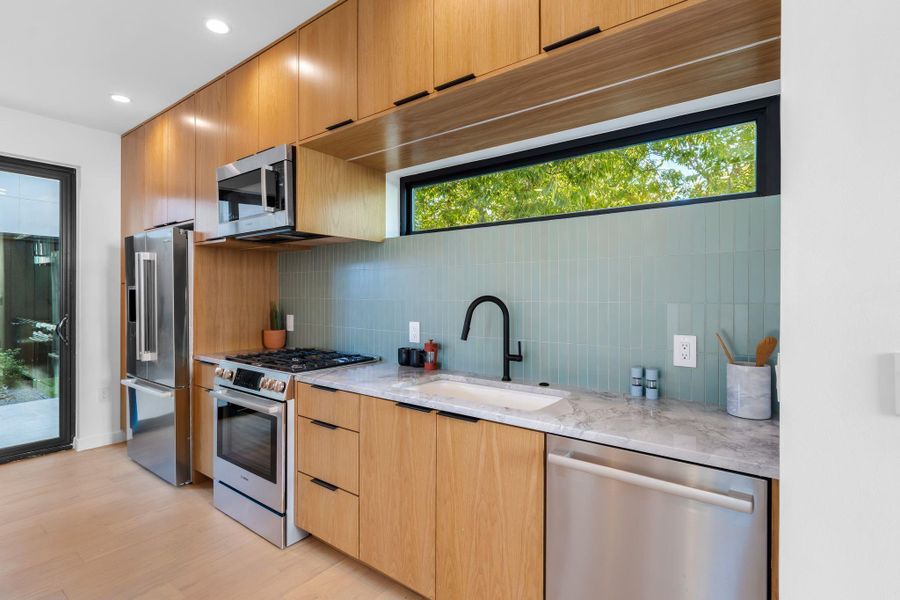 Airy kitchen with stainless steel appliances including refrigerator