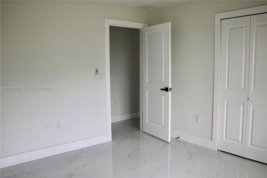 Interior room featuring polished stone-finish tile flooring, white two-panel interior doors, and matte black hardware