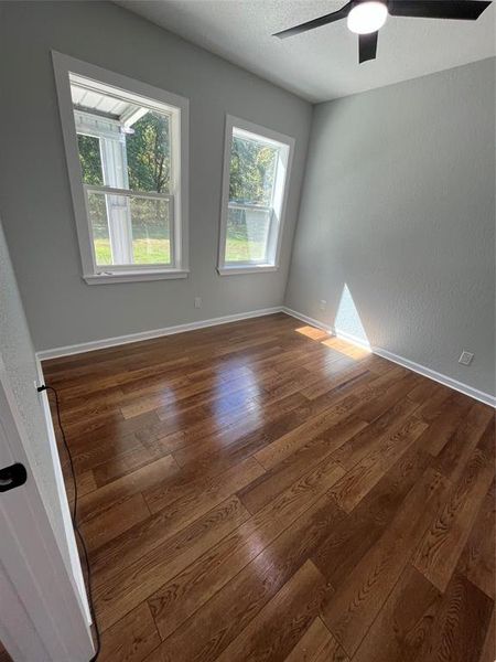 Unfurnished room featuring a textured ceiling, dark wood finished floors, a textured wall, and a ceiling fan Unfurnished room featuring a textured ceiling, dark wood finished floors, a textured wall, and a ceiling fan