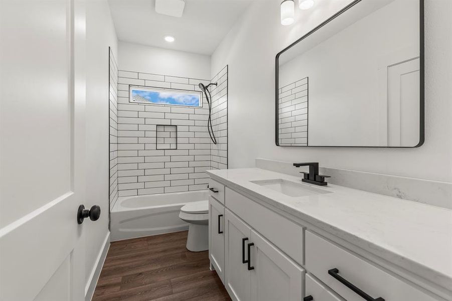 Bathroom featuring vanity, shower / tub combination, wood finished floors, and recessed lighting