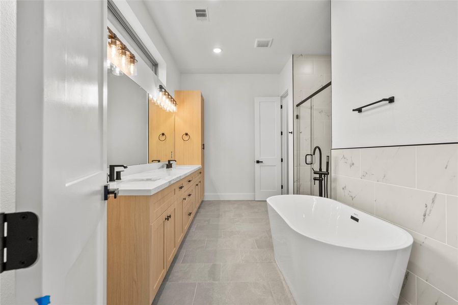 Spa-like primary bathroom with a soaking tub, standing shower, and double sinks Spa-like primary bathroom with a soaking tub, standing shower, and double sinks