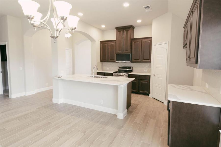 Kitchen with tasteful backsplash, decorative light fixtures, an inviting chandelier, sink, and appliances with stainless steel finishes