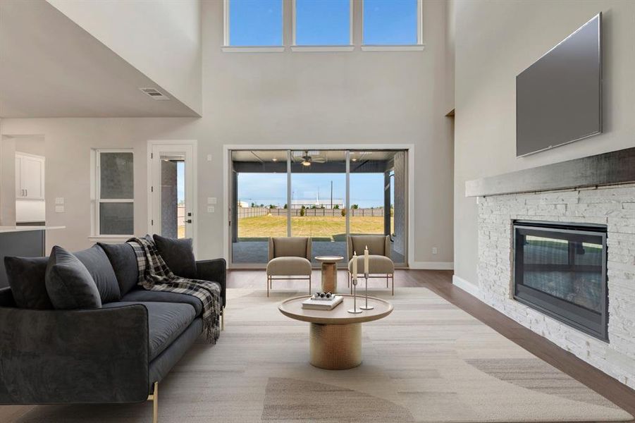 Living room with a fireplace, light wood-type flooring, and a high ceiling Living room with a fireplace, light wood-type flooring, and a high ceiling