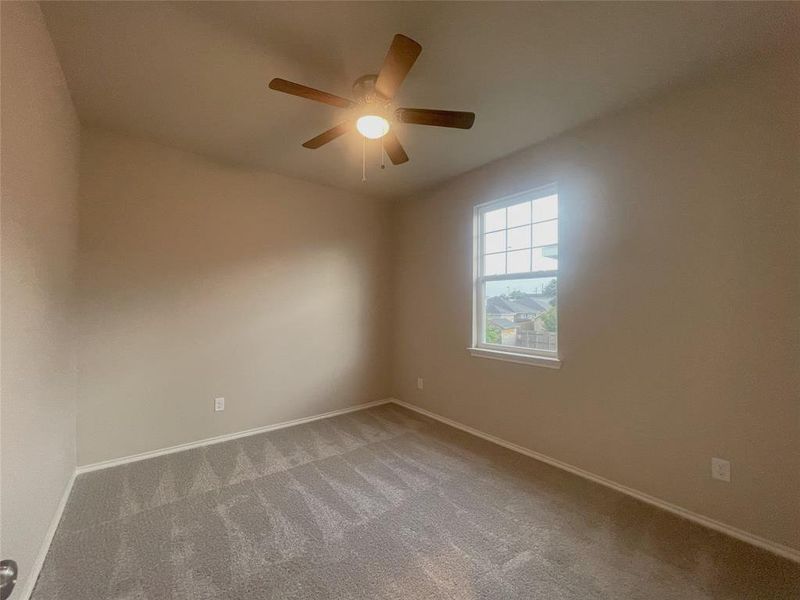 Carpeted empty room featuring ceiling fan and baseboards