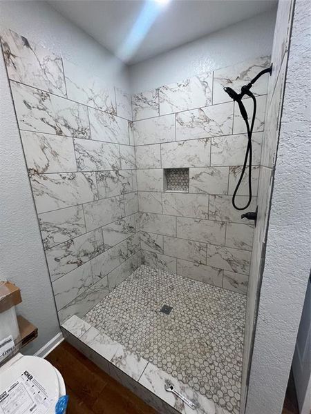 Full bath featuring a textured wall and a shower stall Full bath featuring a textured wall and a shower stall