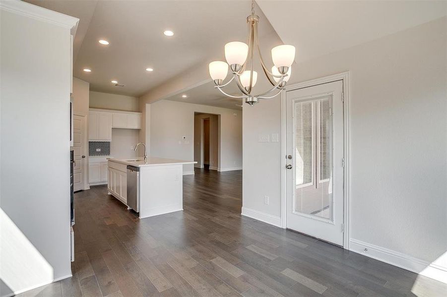 Kitchen featuring sink, decorative light fixtures, a center island with sink, dark wood-type flooring, and an inviting chandelier