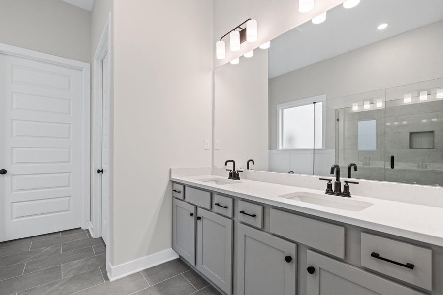Dual vanity with white countertops, matte black fixtures, and light gray cabinetry Dual vanity with white countertops, matte black fixtures, and light gray cabinetry