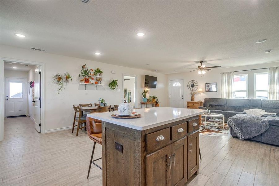 Kitchen featuring a kitchen island, light wood-style tile floors, a kitchen breakfast bar, and recessed lighting Kitchen featuring a kitchen island, light wood-style tile floors, a kitchen breakfast bar, and recessed lighting