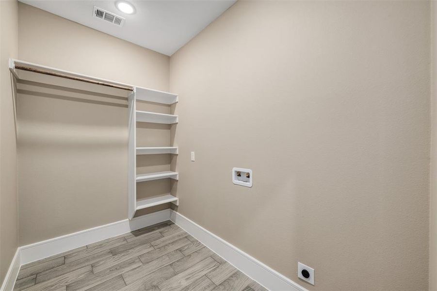 Clothes washing area featuring washer hookup, light hardwood / wood-style floors, and electric dryer hookup